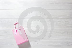 Valentine pink paper giftbag on white wooden background. Top view, copy space valentine`s concept. Birthday gift bag. Romantic