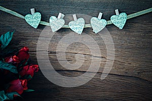 Valentine red roses with hearts on old wood background.