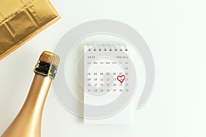 Valentine`s card, a golden bottle of champagne, chocolate in a gold wrapper and a February calendar with a circled date