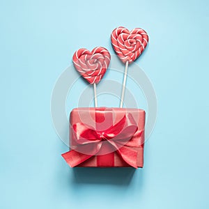 Valentine`s card. Lollipops candy as heart and gift on blue. Funny concept