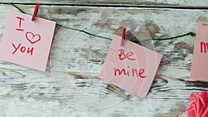 Valentine`s cards with red clips on rustic wood background, 4k dolly shot