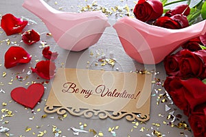 Valentine& x27;s day background. Beautiful bouquet of roses next to letter with text BE MY VALENTINES on wooden table.