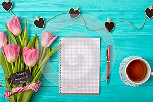 Valentine`s Day background with bouquet of tulips and an empty notebook for romantic entries.