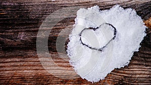 Valentine's Day background. Brown old winter wooden natural boards in with white heart made of snow. Copy space. Top