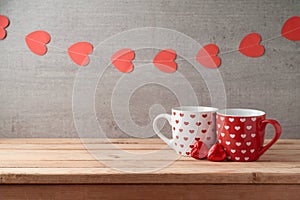 Valentine`s day background with coffee cups, heart shape chocolate and garland