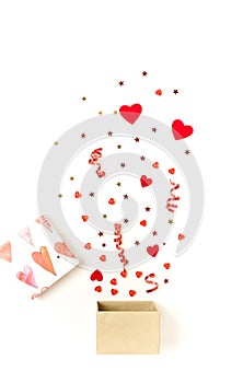 Valentine`s day background.  gift box with various party confetti, red hearts and decoration isolated
