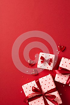 Valentine\'s Day background. Gift boxes with red ribbon bows, hearts, confetti on red background