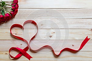 Valentine's day background image with red ribbon beautiful heart shapes and red roses. Resting on a wooden table