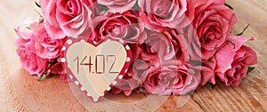 Valentine`s Day background with pink roses over wooden table.