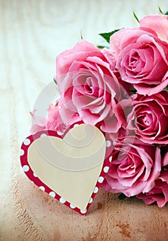 Valentine`s Day background with pink roses over wooden table.