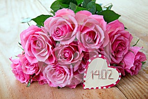 Valentine`s Day background with pink roses over wooden table.