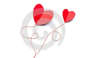Valentine`s Day background. Red paper hearts connected by a thread on a white background, isolated