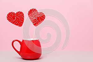 Valentine`s day background. Two heart-shaped candies in a red Cup, a on a light pink background. Greeting card