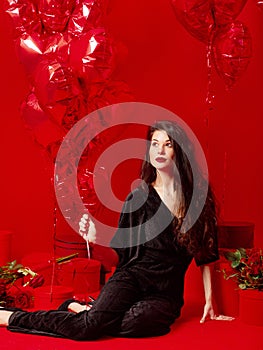 Valentine`s Day. Beauty girl in black with red heart-shaped balloons having fun