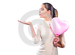 Valentine`s day. Beauty girl with pink heart shaped air balloon pointing hand