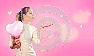 Valentine`s day. Beauty girl with pink heart shaped air balloon pointing hand photo