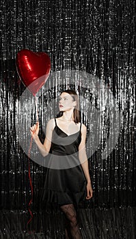 Valentine's Day. Beauty girl with red air balloons on dark background. Beautiful stylish young woman on Holiday
