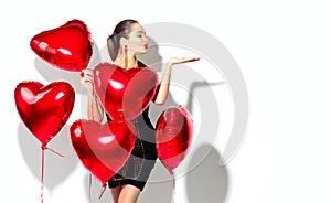 Valentine`s Day. Beauty girl with red heart shaped air balloons having fun
