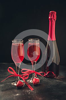 Valentine`s day and birthday greeting card with champagne and heart candy on black.