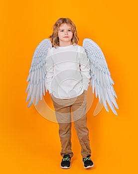 Valentine's day. Blonde cute child with angel wings on a yellow studio background. Happy angel child.