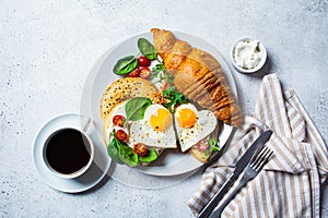 Valentine`s day breakfast concept. Sandwiches with croissant, bagel, cream cheese and fried eggs hearts on white plate, top view