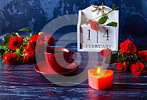 Valentine\'s Day is a calendar date in February. Red cup of coffee, lighted candle, bouquet of red roses.