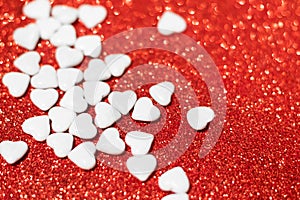 Valentine's day candies on red glitter background. Valentine's day white heart shaped candies