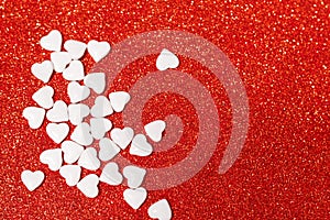 Valentine's day candies on red glitter background. Valentine's day white heart shaped candies