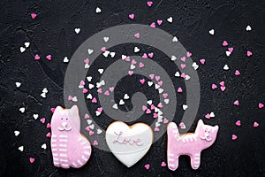 Valentine`s Day candy. Heart shaped cookie with lettering Love and kitty on black background top view