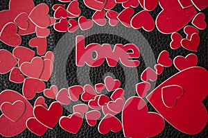 Valentine`s Day card. Colorful red hearts and word love on black leather background