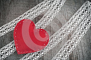 Valentine`s day card. Red felt heart on lace and wooden table background with copy space.