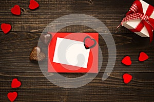 Valentine`s Day card on the wooden background. Gift box, red hearts and chocolate on the wooden desk.