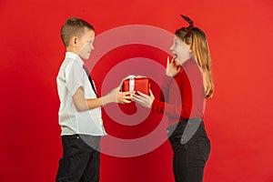 Valentine`s day celebration, happy caucasian kids isolated on red background