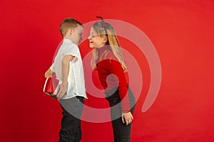 Valentine`s day celebration, happy caucasian kids isolated on red background