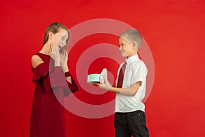 Valentine`s day celebration, happy caucasian kids isolated on red background