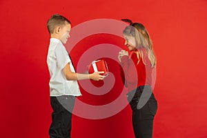 Valentine`s day celebration, happy caucasian kids isolated on red background