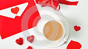 Valentine`s day composition with coffee cup and box of chocolate hearts and envelope with blank note mockup inside on white