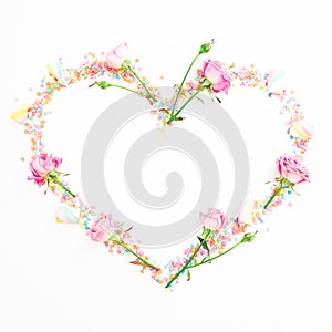 Valentine`s day composition. Heart made of pink flowers and candy confetti on white background. Flat lay, Top view.