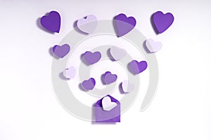 Valentine`s day composition. Pink and violet hearts blowing from envelope on pink background. Love message letter concept