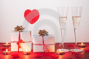 ValentineÃÂ´s day composition .with two glasses of champagne, heart, gifts .and candles on red background. San Valentin and Love