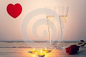 ValentineÂ´s day composition with two glasses of champagne, heart, rose and candles on white wooden background.