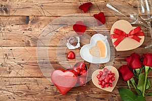 Valentine`s day concept with coffee cup, heart shape chocolate, rose flowers and gift boxes on wooden background