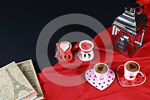 Valentine`s day concept. Coffee in heart shaped cup with candle and notebook on black background.