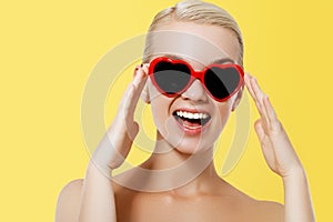 Valentine`s Day concept. Fashion Model girl isolated over yellow background. Beauty stylish blonde woman posing in heart