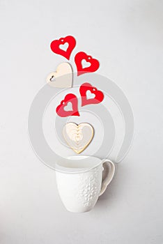 Valentine\'s day concept feelings falling in love. Fullness happiness wooden red hearts from white cup on light background