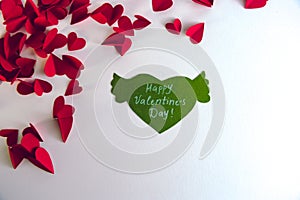 Valentine`s day concept. Green paper heart with wings and congratulation and red hearts on white background.