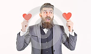 Valentine`s Day concept. Handsome man in formal suit giving red heart standing on white background