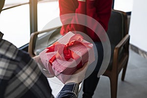 Valentine`s Day concept. Happy man and woman in love presenting gifts to each other at a cafe. A young loving couple celebrating V