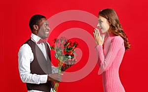 Valentine`s day concept. happy young couple with heart, flowers, gift on red