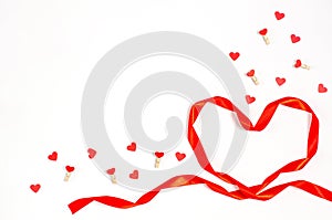 Valentine`s day concept. Heart made of bright red ribbon with decorative clothespins with hearts on a white background